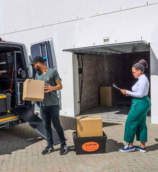 Man loading boxes to a van, while a woman checks her checklist